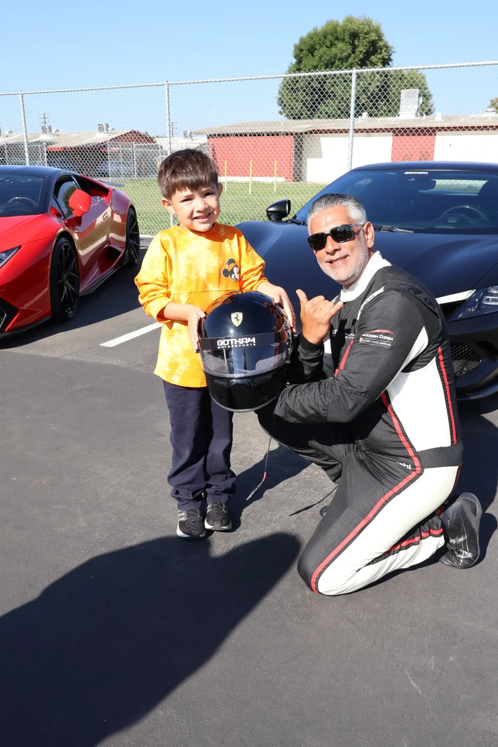 A Gotham Motorsports driver with helmet beside the race car