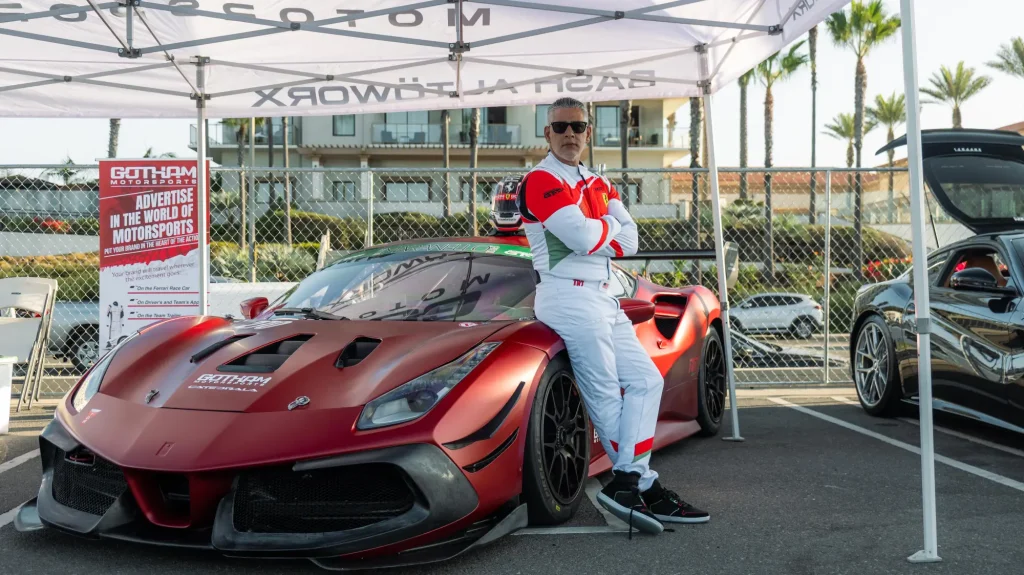 Gotham Motorsports team in race suits beside a red Ferrari at an event
