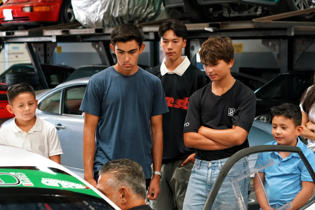 Young visitors gathered around a Gotham Motorsports race car in the garage